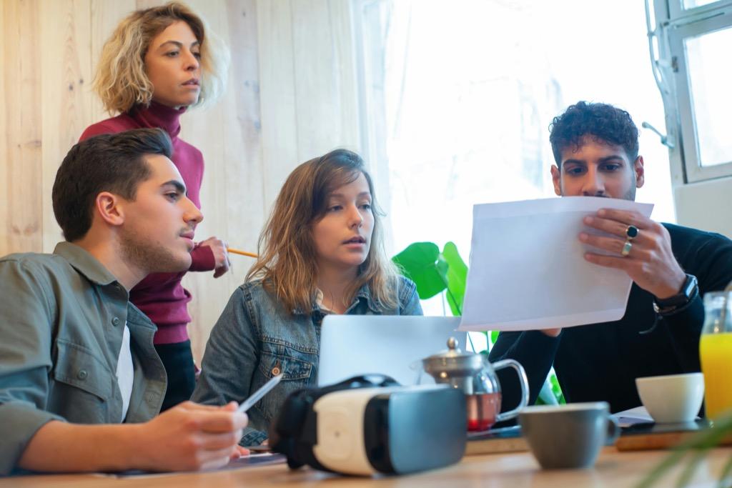 A small team reviews documents and website strategy together around a laptop.