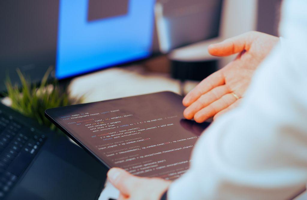 Developer reviewing code on a tablet beside a computer