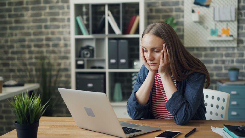 Woman looking concerned while using a laptop at a desk